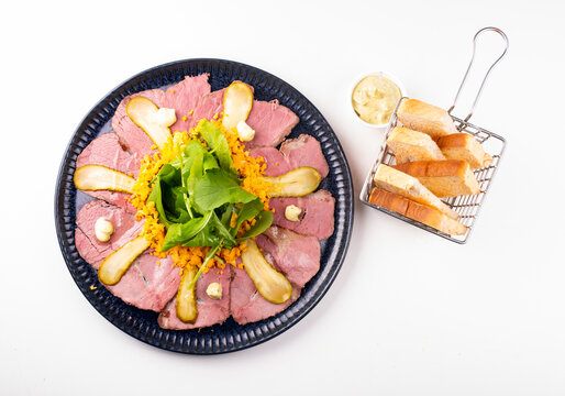 Pastrami and roast beef appetizer with arugula and toast points, top view on a white background.