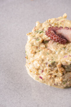 Close-up of a succulent seafood tartare garnished with an octopus tentacle; gourmet studio shot.
