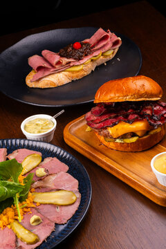 Pastrami festival featuring a cold cut platter, hamburger, and roast beef pastrami bruschetta.