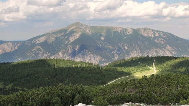 Mountains and trees are visible as sunlight and shadows move across the landscape.