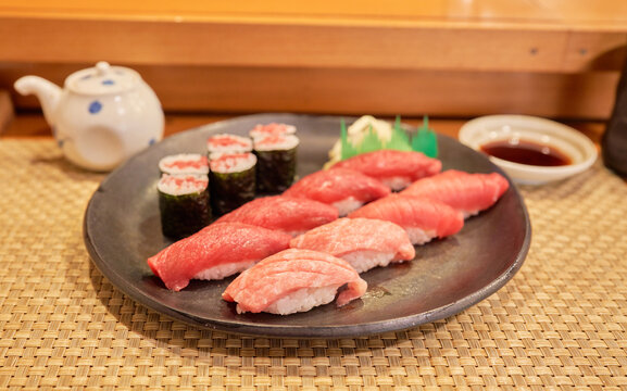 Premium Aomori tuna sushi platter with fatty Otoro, medium Chutoro, and lean Akami nigiri, plus maki rolls, on a black plate in an authentic Japanese dining setting.