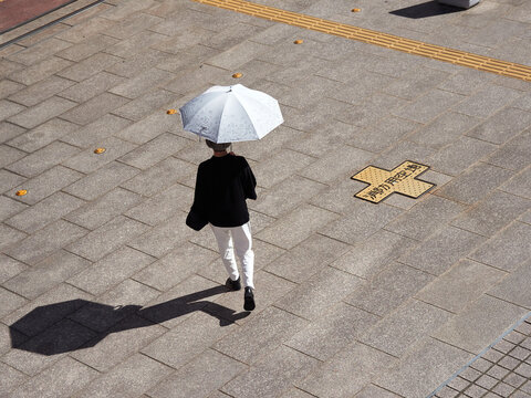 ハイアングルで見た夏の都市の街で歩く一人のシニア女性の姿