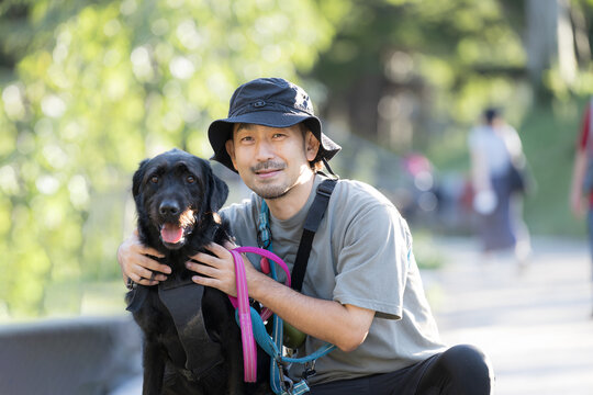 [春～夏イメージ]大型犬と顔を寄せてカメラ目線で笑顔の日本人男性、犬と飼い主の絆、信頼やコミュニケーションイメージ	