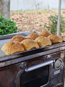 Street food vendor cart with golden baked buns displayed outdoors at a rustic market stall
