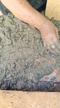 Woman Hands Applying Clay Earth Mix over Bricks in Natural Construction