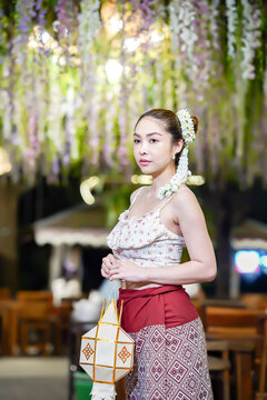 Asian woman in traditional Northern Thai dress holding a Lanna paper lantern.