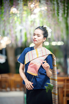 A beautiful Asian woman in traditional Thai attire posing gracefully outdoors.