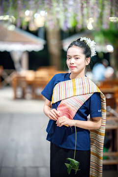 beautiful Asian woman in traditional Thai attire posing gracefully outdoors.