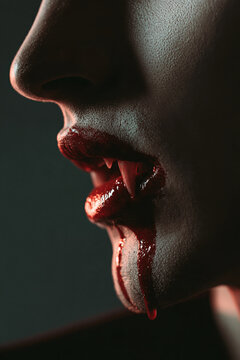 A close-up of a person with vampire fangs dripping with blood, a chilling image evoking fear and the supernatural.