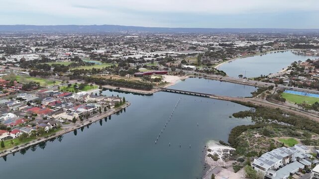 Aerial drone view looking over West Lakes and Tam O'shanter Creek in Adelaide, South Australia. The artificial lake system, connecting railway and road bridge infrastructure, residential houses