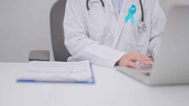 doctor using laptop and report notes on notebook. blue Ribbon concept of November Prostate Cancer Awareness month, Diabetes day , Men Health, International men, Father day. world cancer day