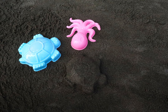 Plastic Sea Animal Sand Molds and Molded Turtle Shape on Black Volcanic Beach Sand