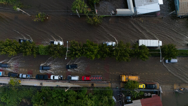 An elevated view of a flooded road with vehicles driving through the water.	