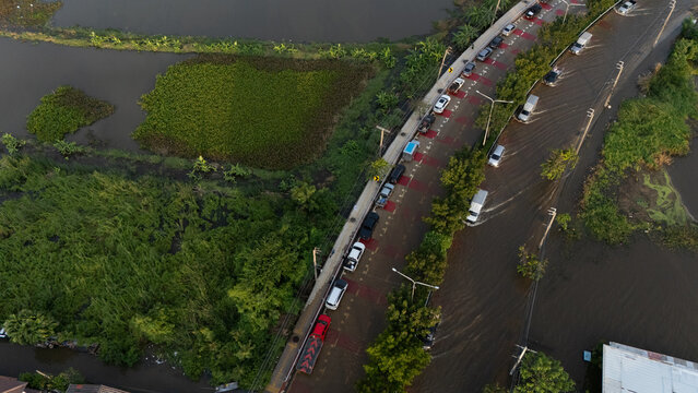 An elevated view of a flooded road with vehicles driving through the water.	