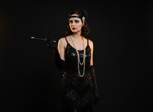 Elegant 1920s flapper woman in black Art Deco dress with pearls and cigarette holder