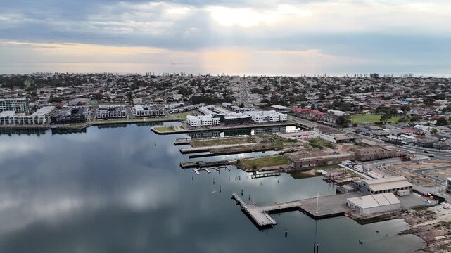 Aerial drone view of waterfront development and harbor basin at New Port, Port Adelaide, South Australia, with townhouses, apartment complexes, historical port infrastructure, and timber wharves