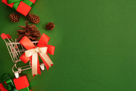 Christmas shopping concept with mini shopping cart and gifts on green background