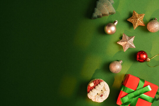 Christmas decorations with gift box and Santa cookie on green background