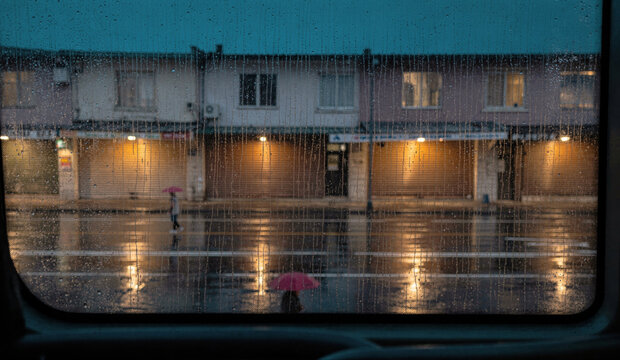 Rainy Evening Street Seen Through Wet Window With Pink Umbrellas