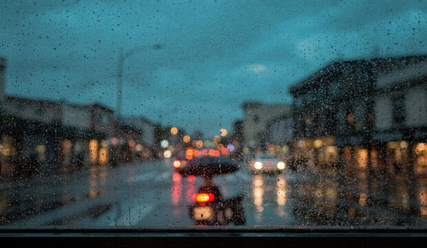 Rainy City Street at Dusk Seen Through Window with Raindrops