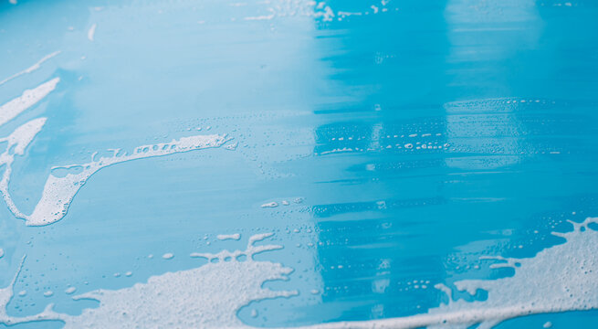 Partly cleared blue surface with foam along the lower edge after a squeegee pass.