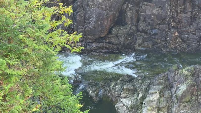 Deep green canyon pool below Cleveland Dam at Capilano River in Vancouver, surrounded by steep rocky cliffs and green forest in a dramatic natural gorge.