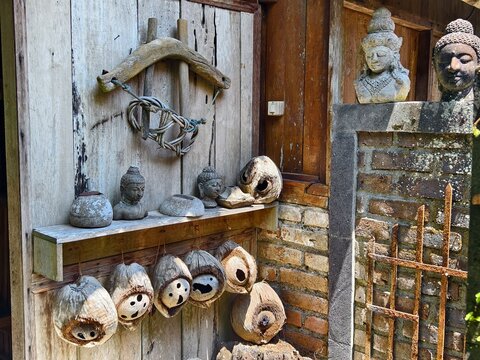  a charming rustic display featuring hand-carved coconut shell masks, traditional stone Buddha, and an antique wooden ox yoke hung