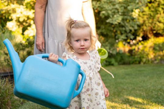 Toddler Posing With Large Blue Watering Can in Garden