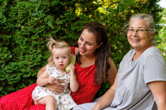 Three Generations Sharing Playful Garden Harvest Moment Together
