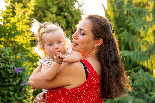Mother Holding Curious Toddler in Golden Summer Garden Light
