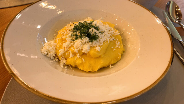 Traditional Ukrainian banosh made from creamy cornmeal and topped with sheep cheese, served on a plate in a restaurant. Authentic cuisine of the Carpathian and western mountainous regions of Ukraine