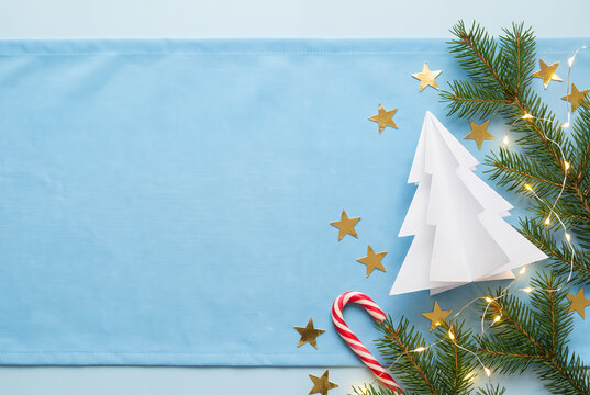 White Christmas tree with gold stars and pine branches on blue background