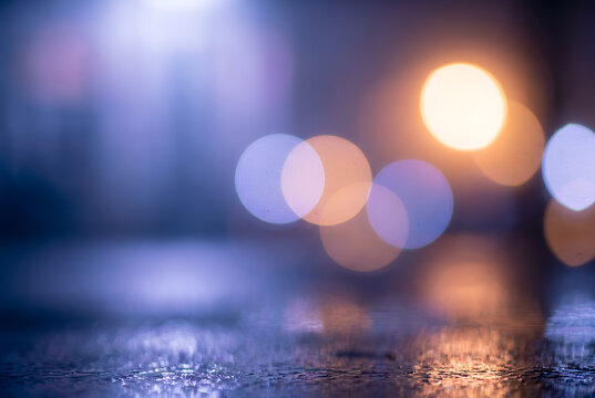 Blurred bokeh lights on wet surface with warm and cool tones