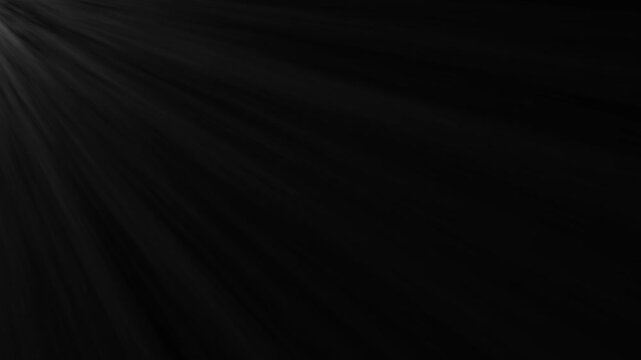 Bright light rays shining from top corner on black background 
