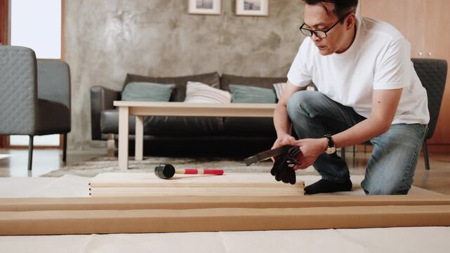 One Asian mature man prepares DIY tools and flat-pack furniture parts, self-assembles in living room, builds for home improvement, wooden craft install hobby workshop, handyman active lifestyle.