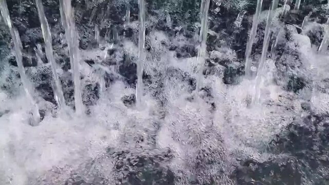 Macro view of water jet streams hitting pool surface with intense frothy foam and air bubbles splash
