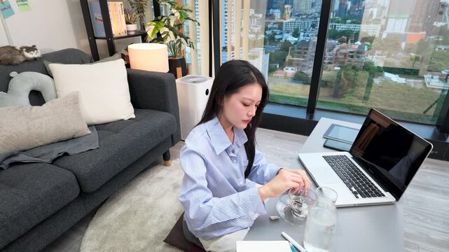 Asian Freelancer Working on Laptop While Preparing Tea in Modern Apartment