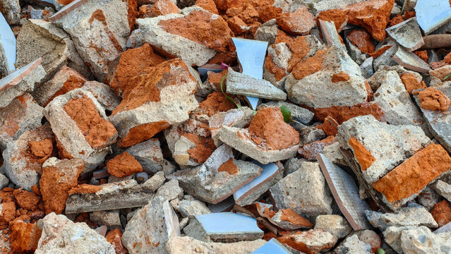 Close-up of scattered construction debris, failure and broken bricks texture background from building renovation, demolition rubble mixed with tiles.