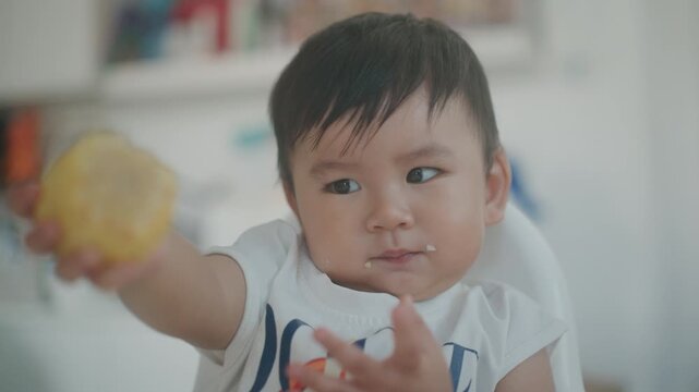 4K Happy Little Asian Toddler Sitting on High Chair and Eating Boiled Corn