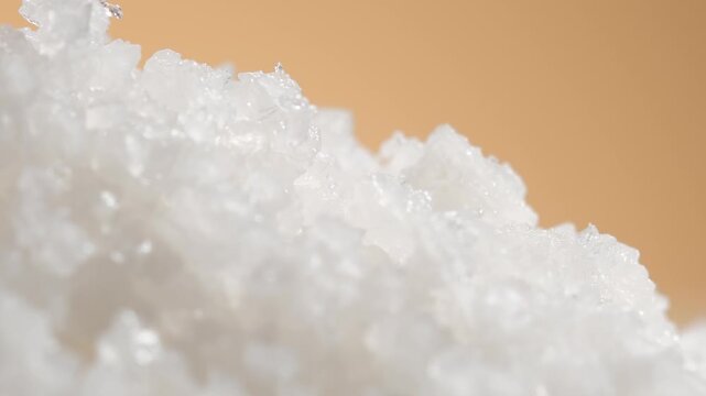 Extreme close-up of white salt crystals rotating 360 degrees, revealing translucent crystalline shapes, fine texture and sparkling highlights for food and seasoning commercial content.