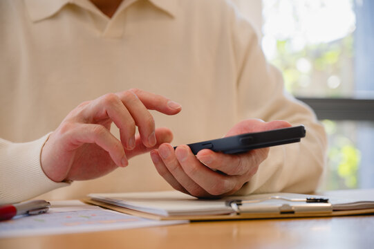 Businessman using smartphone and business data on clipboard analyzing financial and reports, business statistics info graphics, pie charts, checklist for policy implementation featuring a standard
