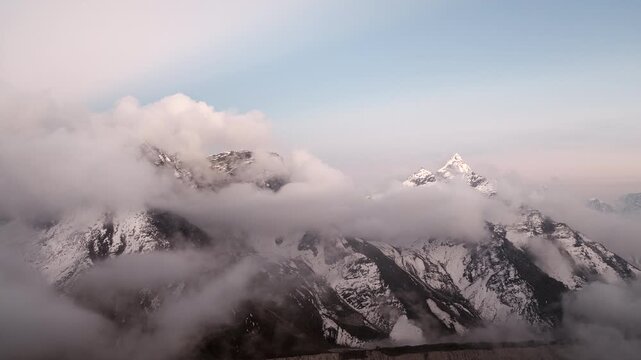 Wide drone shot moving right across the Himalayas as thick clouds drift around snow-covered peaks, creating a dramatic high-altitude landscape in Nepal&rsquo;s Everest region.