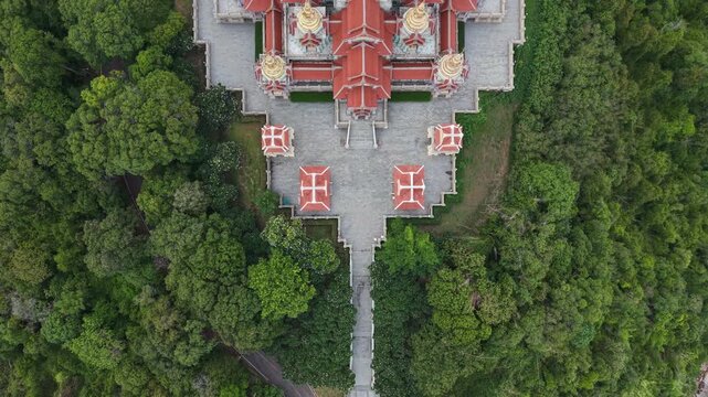 High angle drone panning view reveals the majestic architecture of Phra Mahathat Chedi Phakdee Prakat surrounded by lush green tropical forest in Prachuap Khiri Khan, Thailand