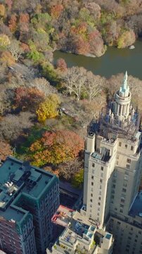 Vertical video: Fly over San Remo building. Large house with two tall towers against autumn colour trees in Central Park. Manhattan, New York City, USA