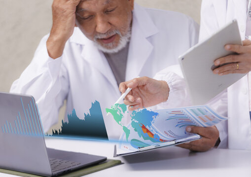 Two doctors analyzing data, one holding tablet and other reviewing report with charts and graphs, both wearing white lab coats, focused and concerned expression