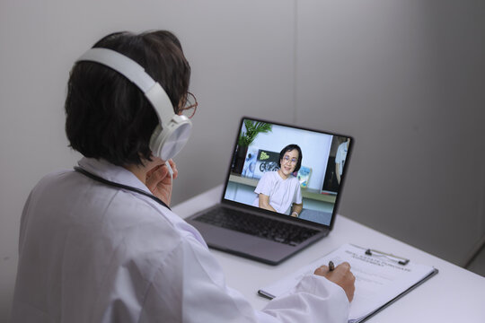 Doctor headphone telemedicine online consultation laptop patient healthcare technology remote communication. Doctor wearing headphone conducting telemedicine consultation with patient laptop