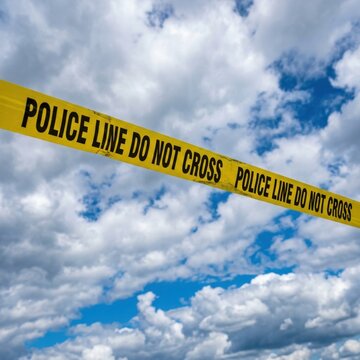 Bright yellow police tape Do Not Cross against a cloudy sky emphasizing restriction and safety