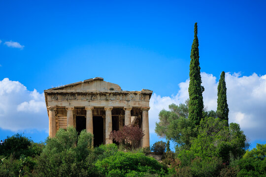 ancient temple of hephaestus among green trees under blue sky in ancient agora athens greece
