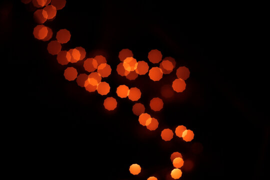 Abstract red and orange bokeh light orbs glowing against a dark black background