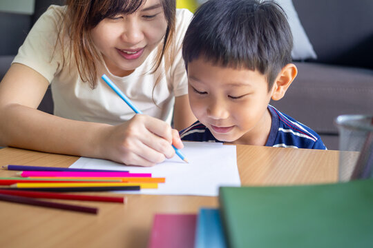 Happy Asia child play and learn drawing picture and cartoon. Funny family is happy and excited in the house. Mother and son having fun spending time together. Holiday, Activity